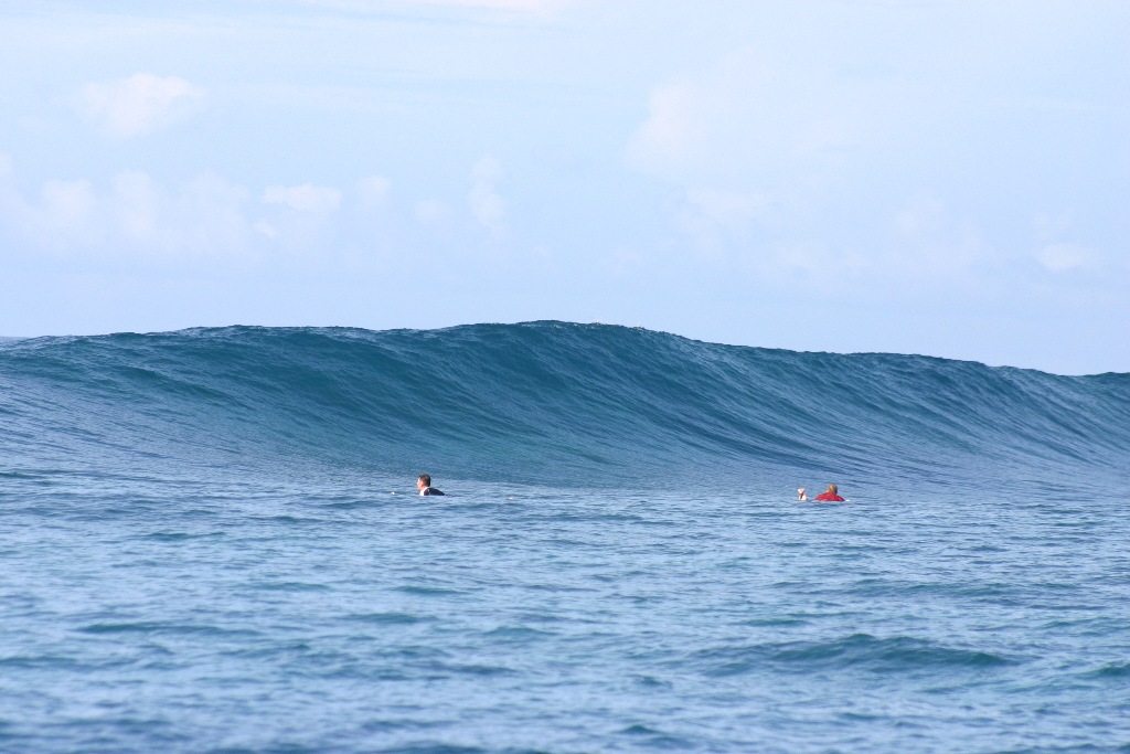 Large wave about to break, two surfers in the water in Samoa, one of the best places to surf in September