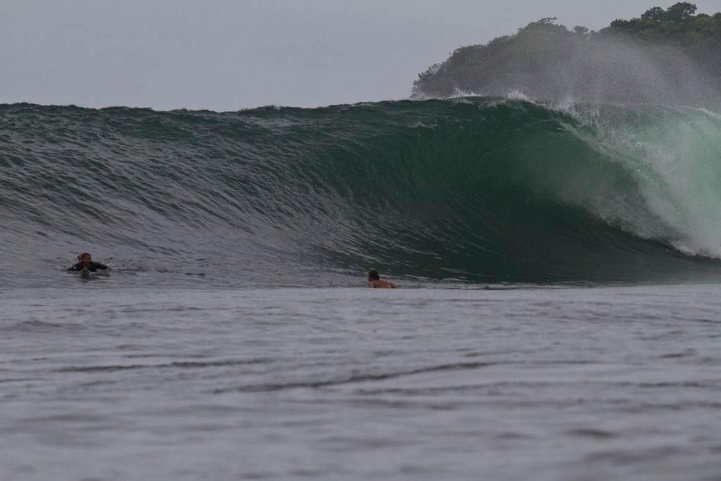 Huge, barreling wave breaking in front of surfers, Santa Catalina Panama surf